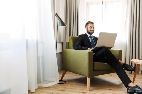 Vonzó fiatal üzletember öltönyt ül egy széken — Stock Fotó