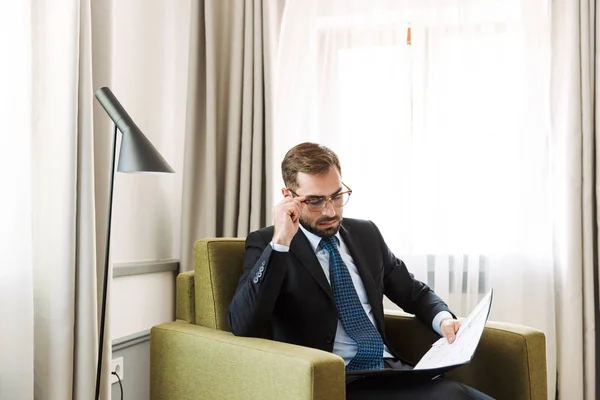 Attraktiv ung affärsman klädd i kostym sitter i en stol — Stockfoto