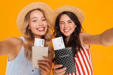 Pasaport ve seyahat bileti tutarken selfie fotoğrafı çeken hasır şapka giyen genç kadınların portresi