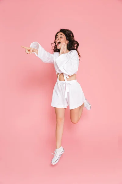 Felice giovane donna emotiva eccitato saltando isolato su sfondo muro rosa . — Foto Stock