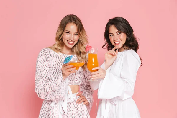 Jovens mulheres bonitas amigos posando isolado sobre fundo de parede rosa bebendo coquetéis . — Fotografia de Stock