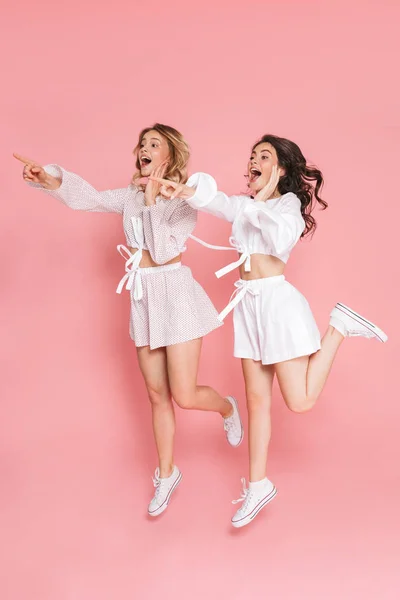 Giovane allegro emotivo amici felici donne saltando isolato su sfondo muro rosa . — Foto Stock