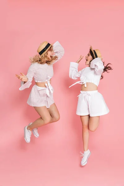 Young glada känslomässiga lyckliga vänner kvinnor hoppar isolerade över rosa vägg bakgrund. — Stockfoto