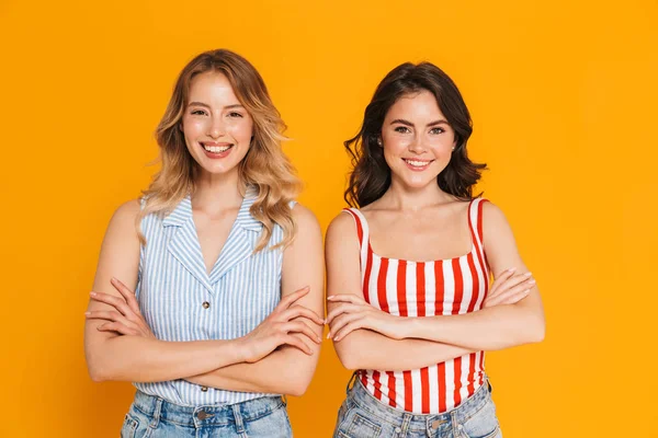 Porträtt av två lyckliga blonda och Brunette kvinnor 20s på sommaren slitage leende på kamera med armarna korsade — Stockfoto