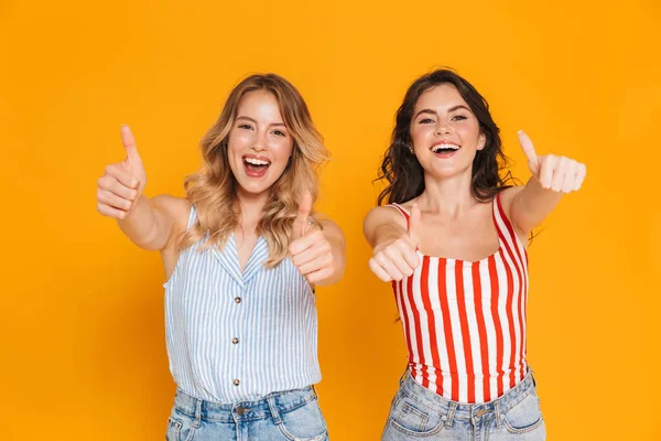 Retrato de dos mujeres rubias y morenas alegres de 20 años en verano llevan sonriendo mientras muestran los pulgares hacia arriba —  Fotos de Stock