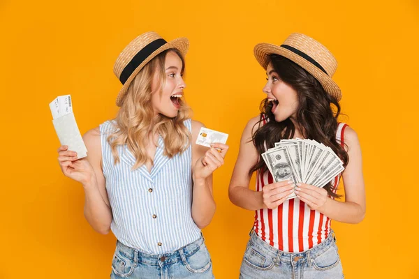 Porträt glücklicher Frauen mit Strohhüten, die Kreditkarten- und Geldscheine mit Reisepass und Fahrkarte in der Hand halten — Stockfoto