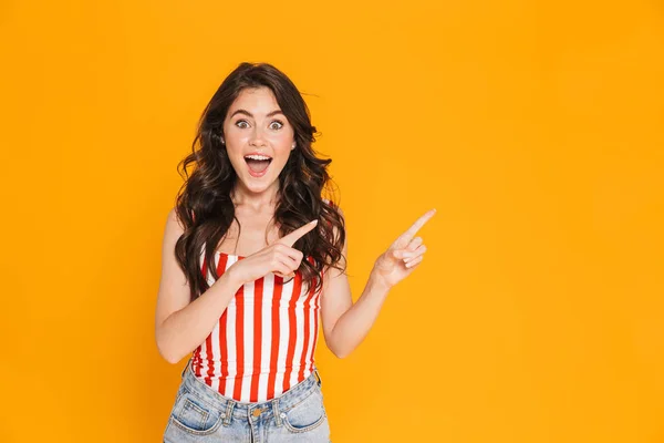 Retrato de mulher surpreendida em camiseta listrada sorrindo para a câmera e apontando os dedos para o lado — Fotografia de Stock