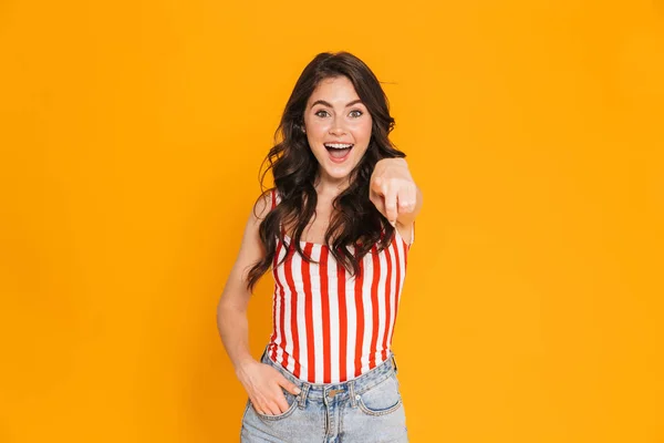 Portret van gelukkige jonge vrouw in gestreepte t-shirt kijken naar camera en wijzende vinger op de camera met haar hand in zak — Stockfoto