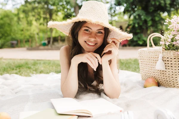 Foto einer glücklichen jungen Frau mit Strohhut beim Lesen von Büchern — Stockfoto