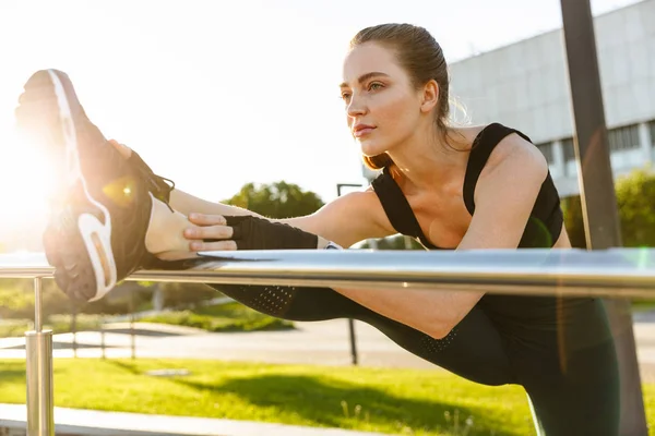 Image of energetic sporty woman leaning on railing and stretchin — Stock Photo, Image