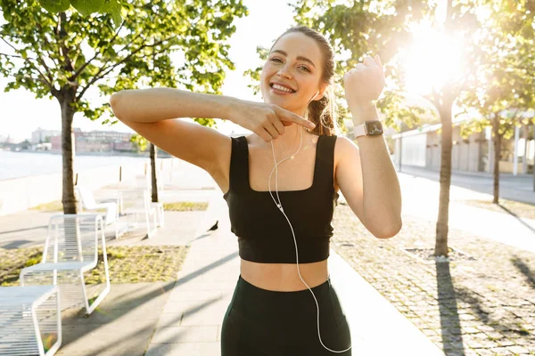 Imagen de una hermosa deportista escuchando música con auriculares — Foto de Stock