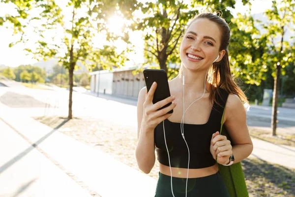 Wizerunek kobiecego Sportsmen trzymający smartfon i słuchanie muzyki t — Zdjęcie stockowe