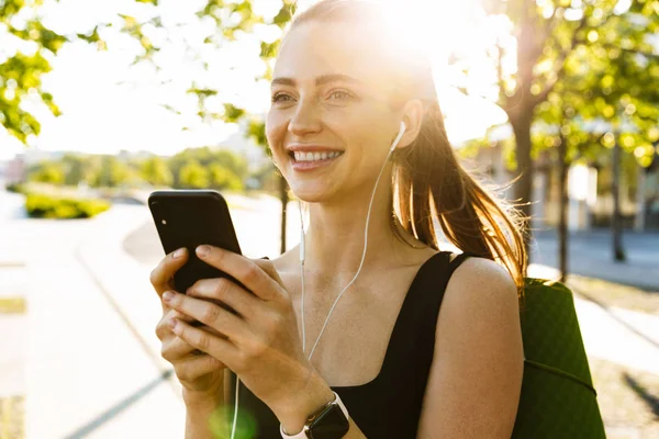 Imagem da bela esportista segurando smartphone e ouvindo — Fotografia de Stock