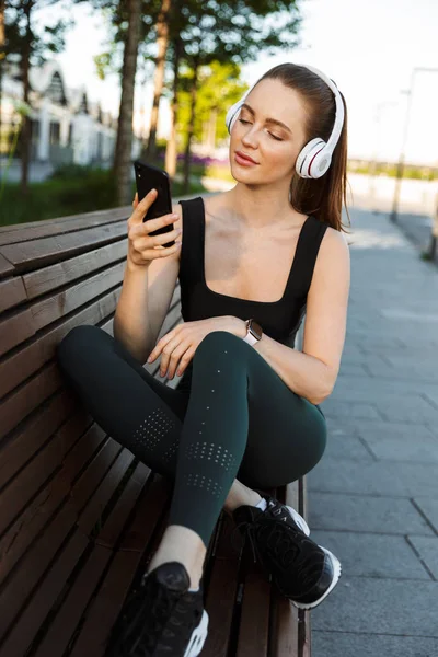 Imagen de deportista atlética sosteniendo smartphone y escuchando — Foto de Stock