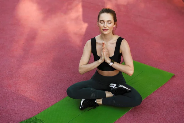 Foto di donna sportiva calma che tiene insieme le palme e medita — Foto Stock