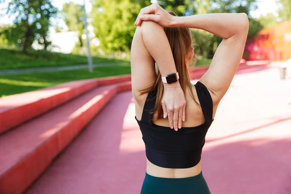 Zdjęcie z tyłu szczupły młody kobieta noszenie zegarek na rękę stretchin — Zdjęcie stockowe