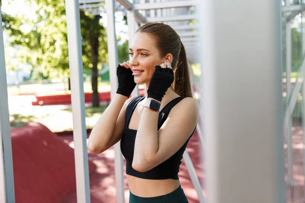 Foto van slanke jonge vrouw dragen earpods en het doen van training met — Stockfoto