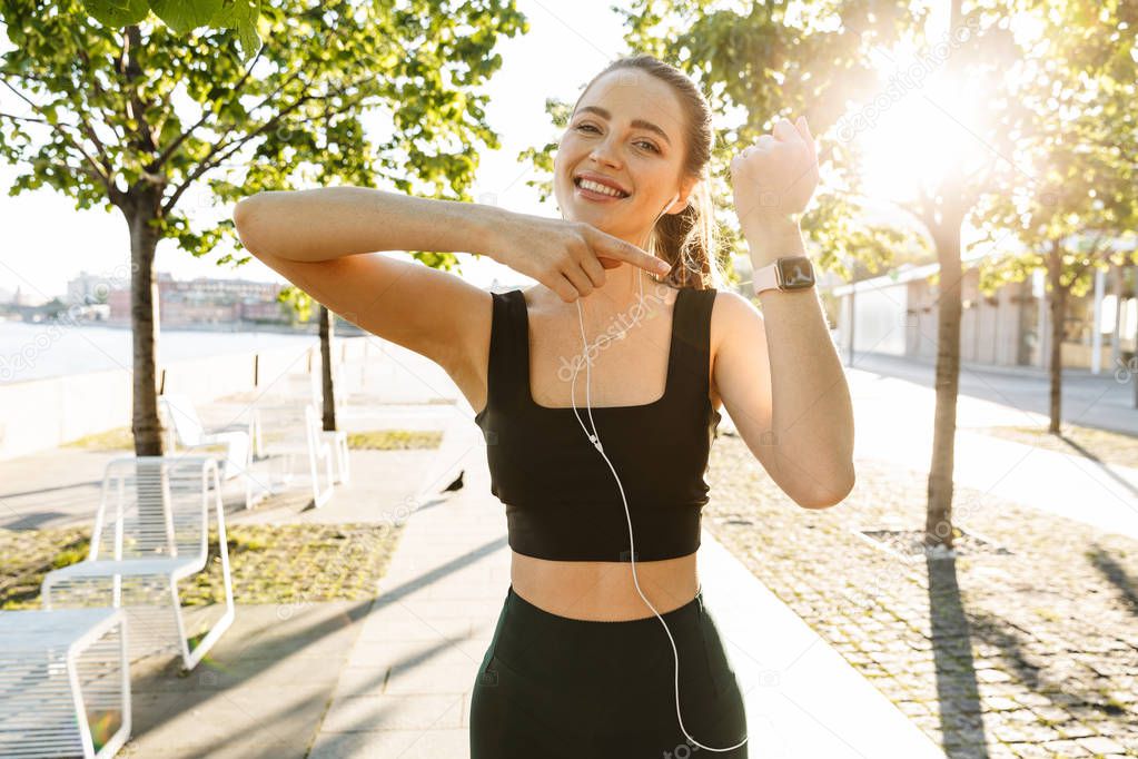 Image of beautiful sportswoman listening to music with earphones