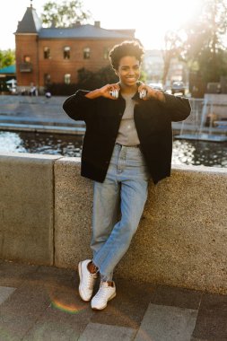 Nehir kenarında yürürken çekici Afrikalı-Amerikalı kadın olding kulaklık portresi