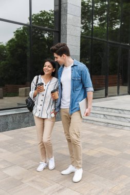 Mutlu heyecanlı inanılmaz sevgi dolu çift öğrenciler sokakta dışarıda birbirleriyle konuşurken kahve içerek yürüyüş.