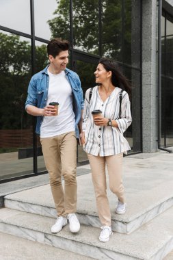 Şehir caddesinde gezinirken paket kahve içen beyaz çiftin görüntüsü