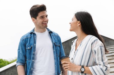 Açık havada merdivenlerden aşağı yürürken kağıt bardak gülümseyen ve konuşurken mutlu çift Görüntü