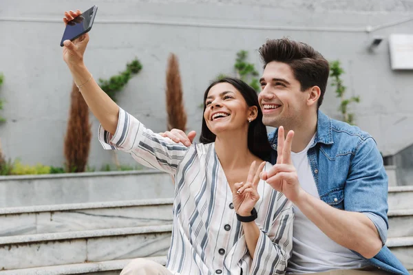 Sorrindo alegre jovem casal amoroso ao ar livre tirar uma selfie por telefone celular . — Fotografia de Stock