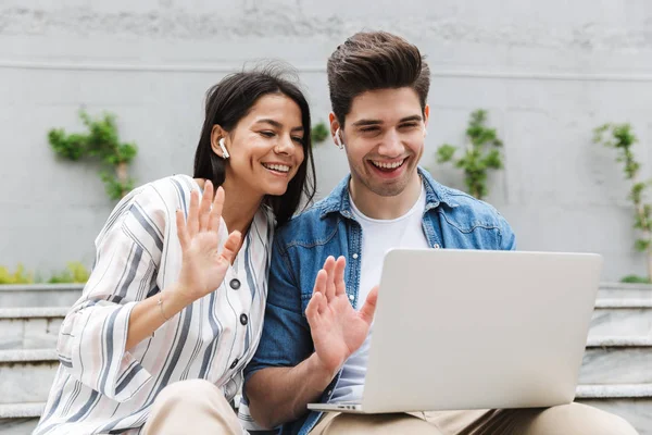 Szczęśliwy młody niesamowite kochający para biznes ludzie koledzy zewnątrz zewnątrz u kroki przy pomocy laptop rachmistrz machając rozmowa rezygnować rodzina albo przyjaciele. — Zdjęcie stockowe