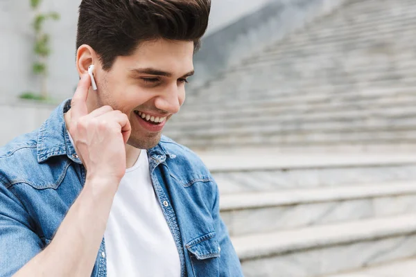 Happy young amazing man businessman posing outdoors outside listening music with earphones. — Stock Photo, Image