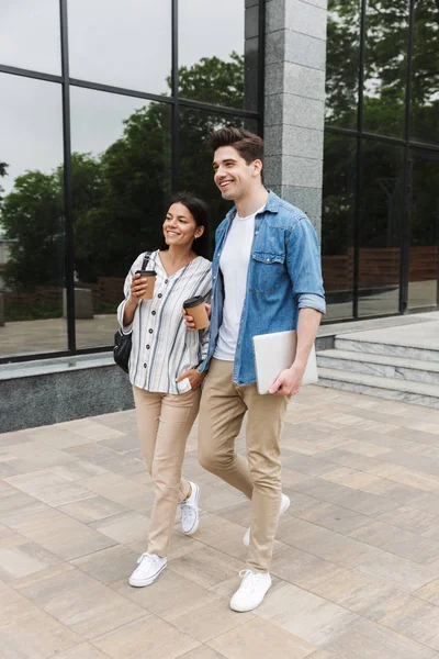 Ευτυχισμένο ενθουσιασμένο καταπληκτικό ζευγάρι φοιτητών έξω στο δρόμο περπάτημα πίνοντας καφέ που μιλάει μεταξύ τους. — Φωτογραφία Αρχείου