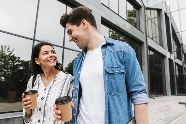 Feliz emocionado increíble pareja amorosa estudiantes al aire libre en la calle caminando beber café hablando entre sí . — Foto de Stock