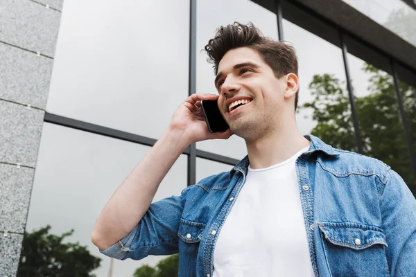 Happy young amazing man businessman posing outdoors outside walking talking by mobile phone. — Stock Photo, Image