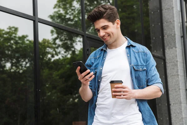 Szczęśliwy młody niesamowity człowiek biznesmen pozowanie na zewnątrz chodzenie rozmowa przez telefon komórkowy picie kawy. — Zdjęcie stockowe