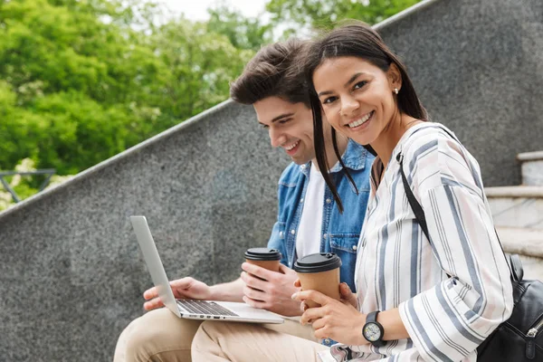 Increíble pareja amorosa gente de negocios colegas al aire libre al aire libre en los pasos utilizando ordenador portátil beber café . — Foto de Stock