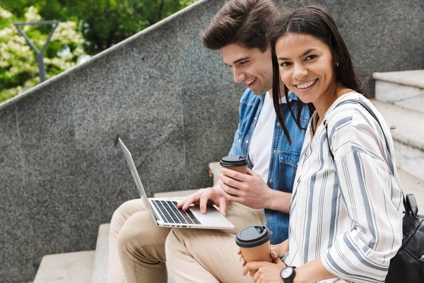 Increíble pareja amorosa gente de negocios colegas al aire libre al aire libre en los pasos utilizando ordenador portátil beber café . — Foto de Stock