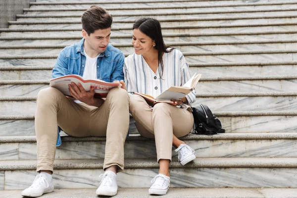 Εκπληκτική αγάπη ζευγάρι φοιτητών σε εξωτερικούς χώρους έξω σε βήματα διαβάζοντας βιβλίο γράφοντας σημειώσεις μελετώντας. — Φωτογραφία Αρχείου