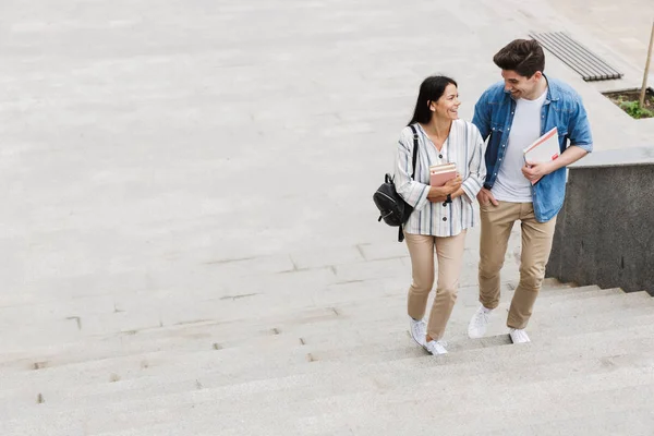 Increíble pareja amorosa estudiantes al aire libre caminando por los pasos con libros . — Foto de Stock