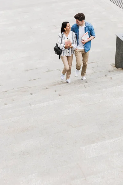 Incroyable couple d'étudiants aimants à l'extérieur marchant par étapes avec des livres . — Photo
