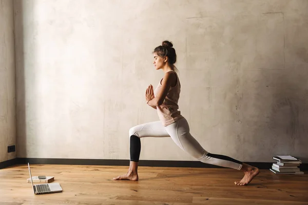 Foto av koncentrerad kvinna gör yoga övningar med slutna ögon och palmer tillsammans hemma — Stockfoto
