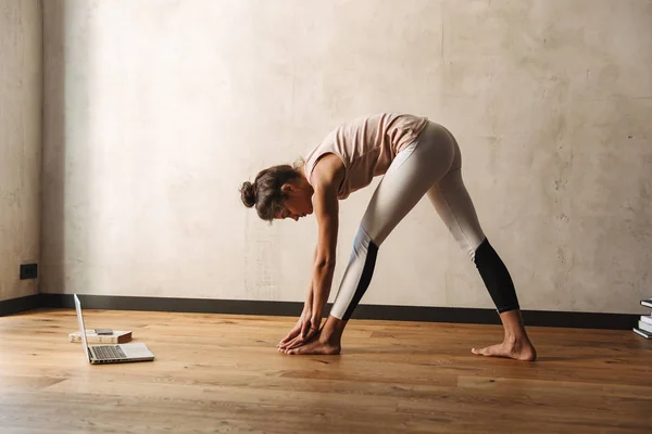 Foto av fokuserad smal kvinna som sträcker sin kropp och gör yoga övningar hemma — Stockfoto