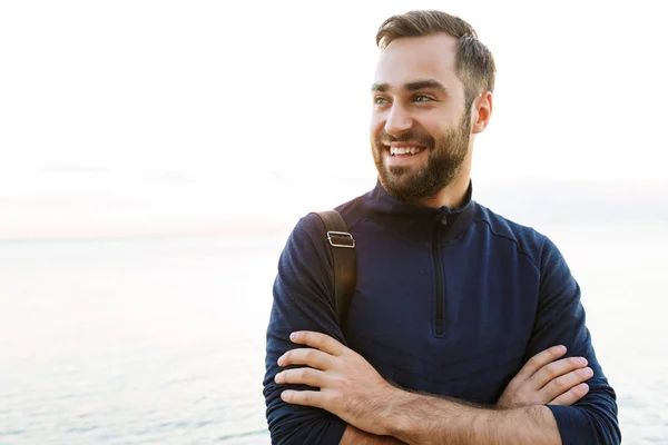 Guapo joven deportista en forma llevando bolsa de pie — Foto de Stock