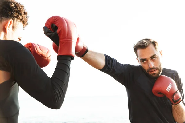Sério bonito forte dois jovens esportes homens boxers amigos na praia perto do mar boxe . — Fotografia de Stock