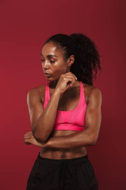 Konsantre güçlü genç afrika fitness spor kadın kırmızı duvar arka plan üzerinde izole poz germe egzersizleri yapmak.