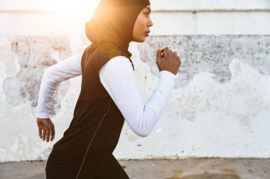 Güçlü Müslüman spor fitness kadın başörtüsü ve koyu giysiler açık havada çalışan giymiş.