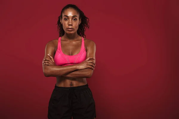 Forte jovem Africano fitness esportes mulher posando isolado sobre fundo da parede vermelha . — Fotografia de Stock