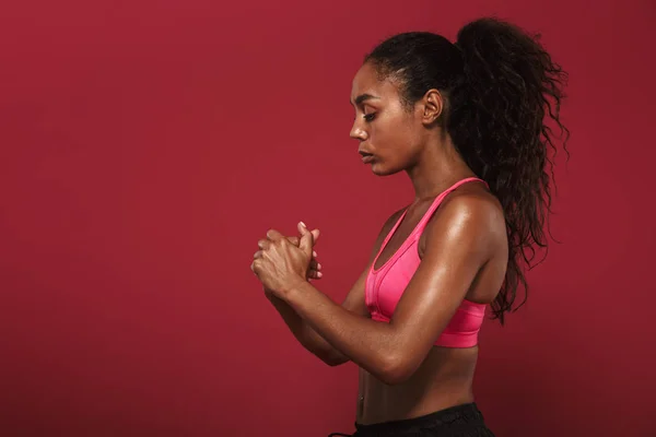 Ernste starke junge afrikanische Fitness-Frau posiert isoliert über roter Wand Hintergrund wärmen ihre Hände. — Stockfoto