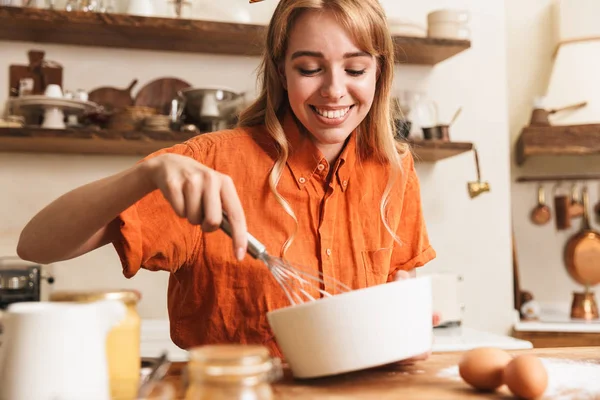 Boldog vidám fiatal szőke lány séf főzés a konyhában. — Stock Fotó