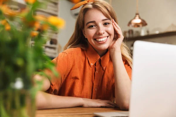 Alegre feliz sorrindo jovem loira na cozinha usando computador portátil . — Fotografia de Stock