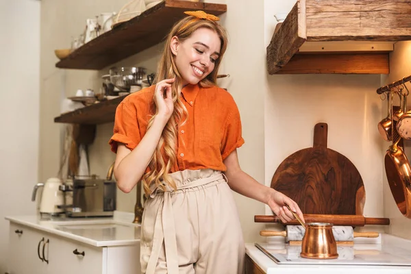 Örömmel mosolygott vidám fiatal szőke lány séf a konyhában főzés. — Stock Fotó