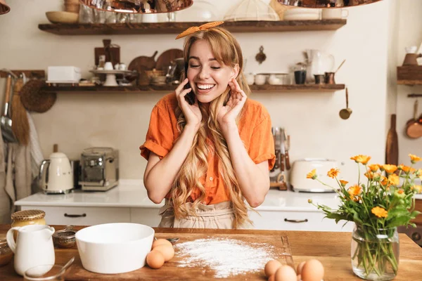 기쁘게 행복 미소 젊은 금발여자 요리사 요리 에서 부엌 이야기 로 휴대 전화. — 스톡 사진